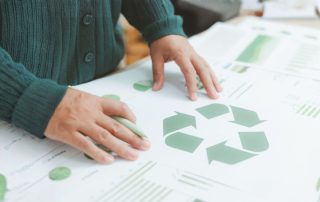 Mani appoggiate su un progetto con il simbolo verde del riciclo