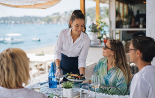 cameriera che serve un piatto di cozze durante un pranzo vista mare